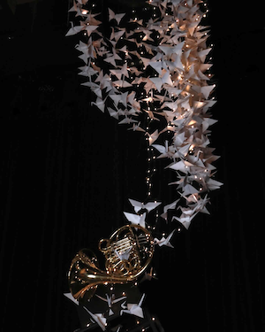 sculture of folded paper cranes, lights and french horn