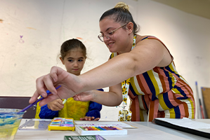 teacher showing younger student how to paint