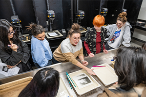 students gathers around professor discussing photograph developing